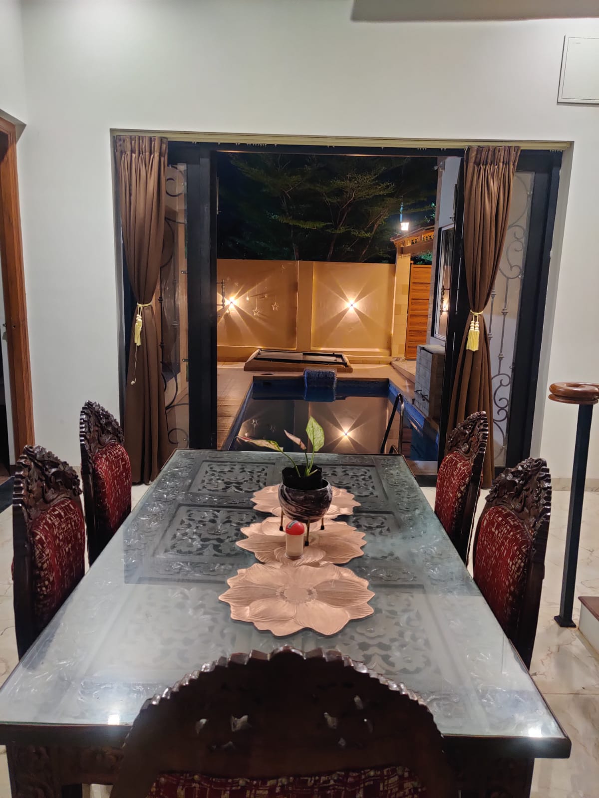 Carved wood dining table with pool view through arched doorway